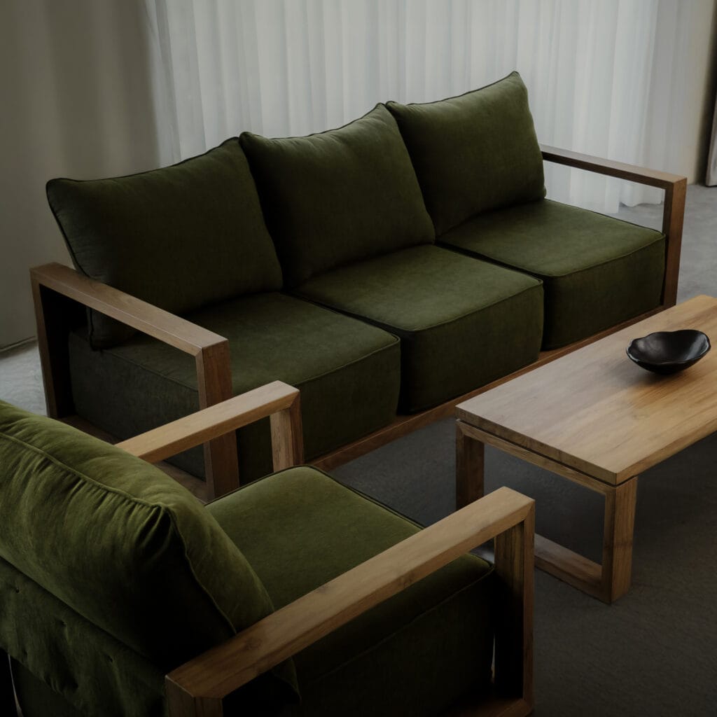 This image shows Nusantara Lifestyle's reclaimed teak sofas and coffee table. The sofas have a dark green covering and are a great example of how sustainable furniture can still look extremely modern.