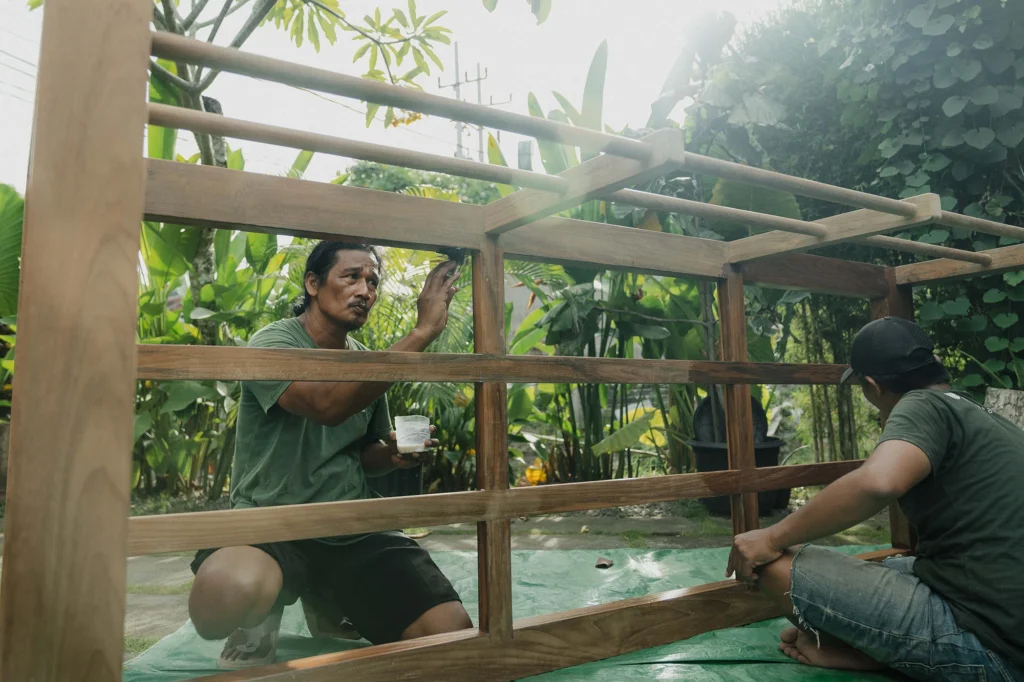 Indonesian artisan hand-finishing reclaimed teak at Nusantara Lifestyle workshop