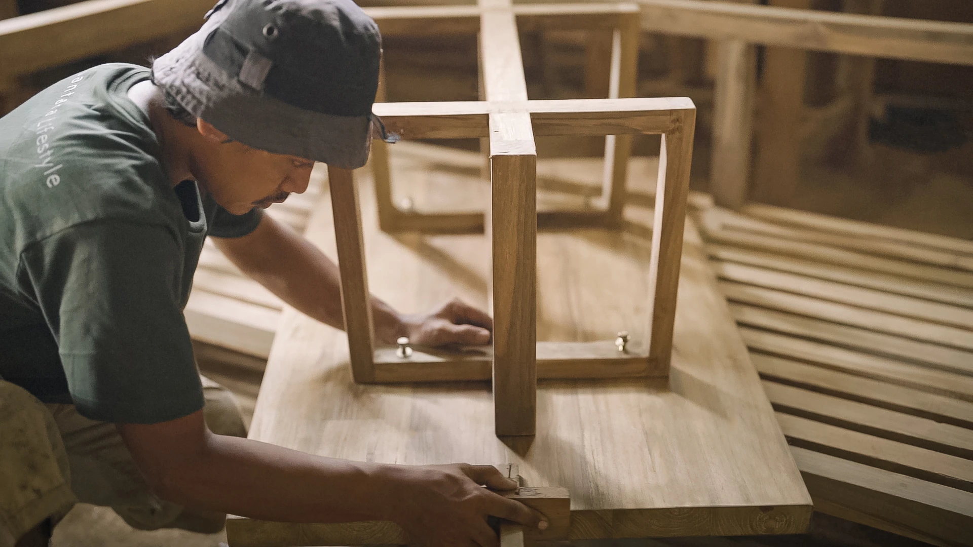 reclaimed-furniture-finishing-process-on-warehouse-by-hands Artisan hand finishing reclaimed teak furniture in workshop for sustainable design.