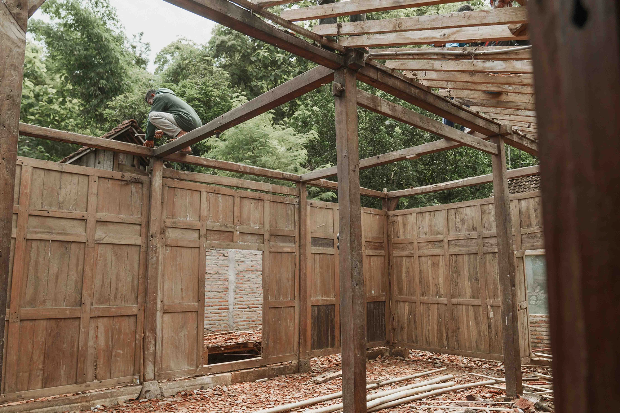 Workers dismantling a traditional Javanese wooden house in Java to reclaim teak timber for sustainable furniture.