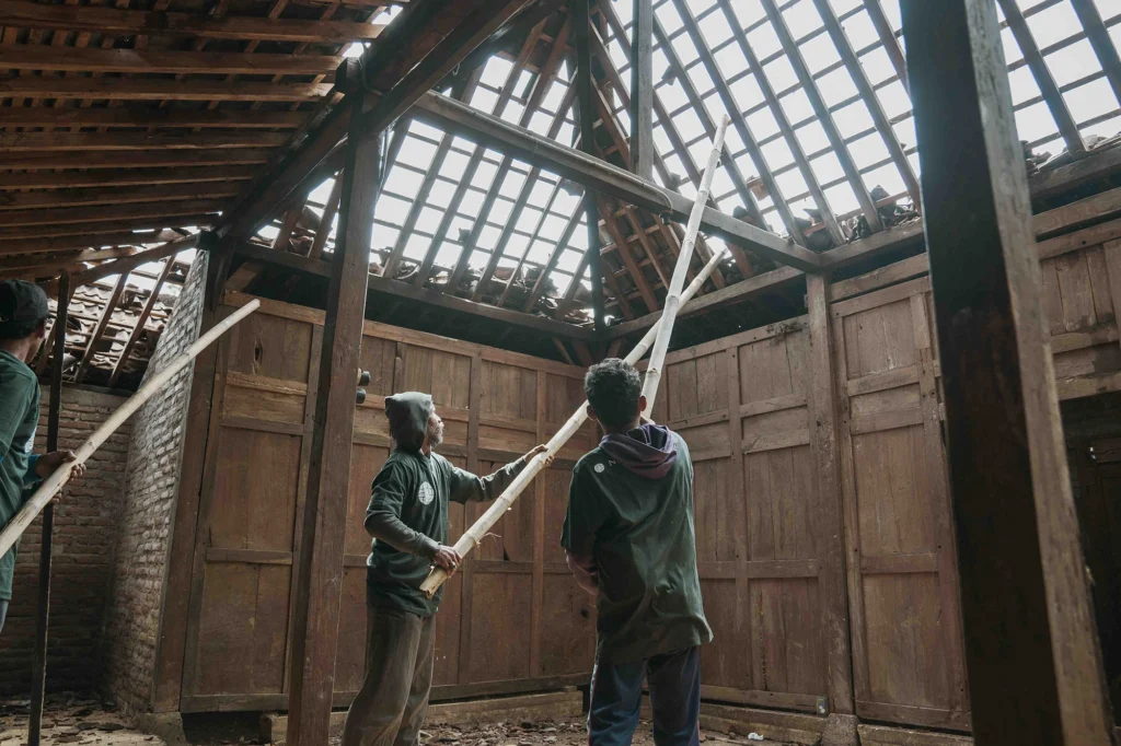 Local craftspeople dismantling a traditional Javanese teakwood house in Central Java for timber salvage.