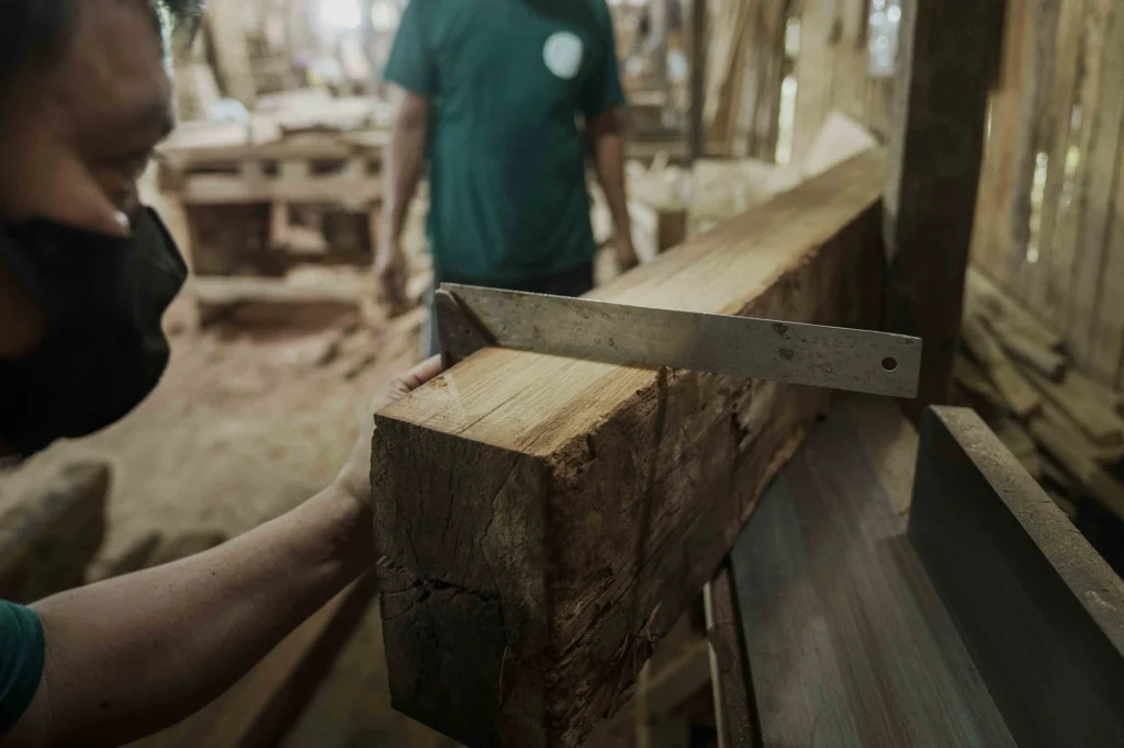One of Nusantara Lifestyle’s skilled craftspeople preparing reclaimed timber to be made into furniture.