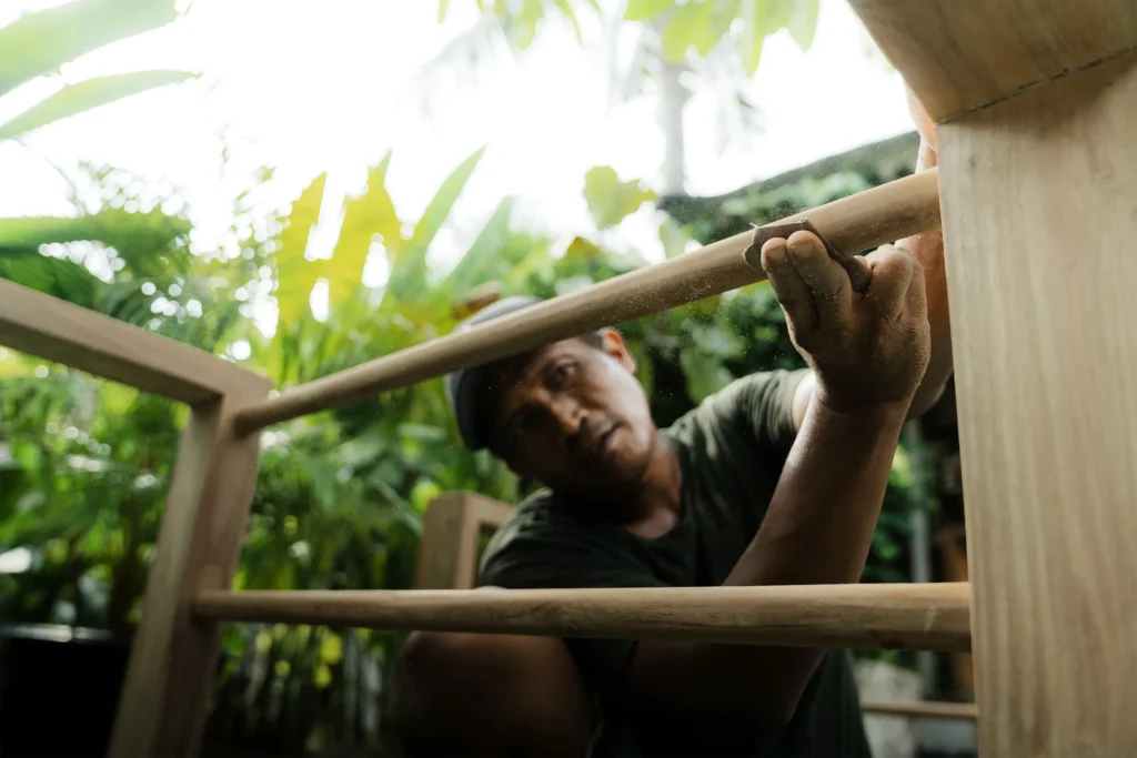 Skilled artisan working on reclaimed teak in the Nusantara Lifestyle workshop.