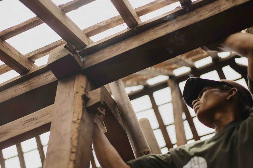A Nusantara Lifestyle worker dismantling a joglo made from teak that has spent decades drying, making it more durable than new plantation teak
