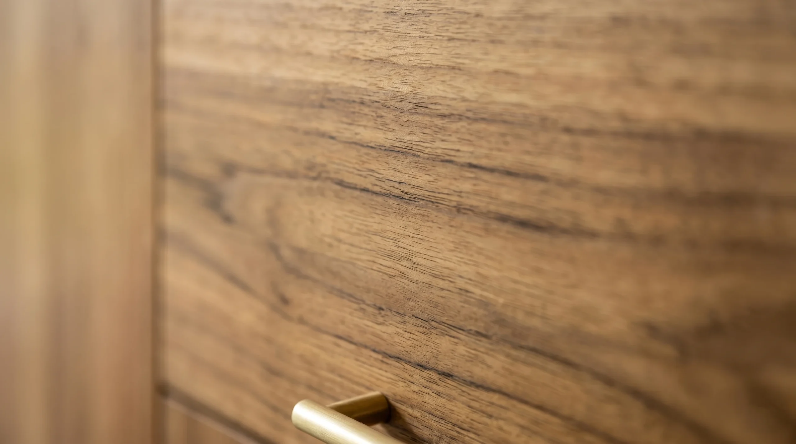 Close-up of reclaimed teak wood grain showing natural patina and matte finish on solid timber cabinetry.