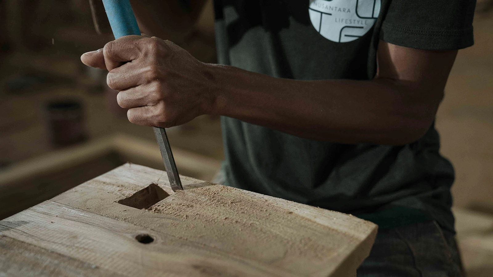 Craftsman processing reclaimed teak timber in a furniture workshop