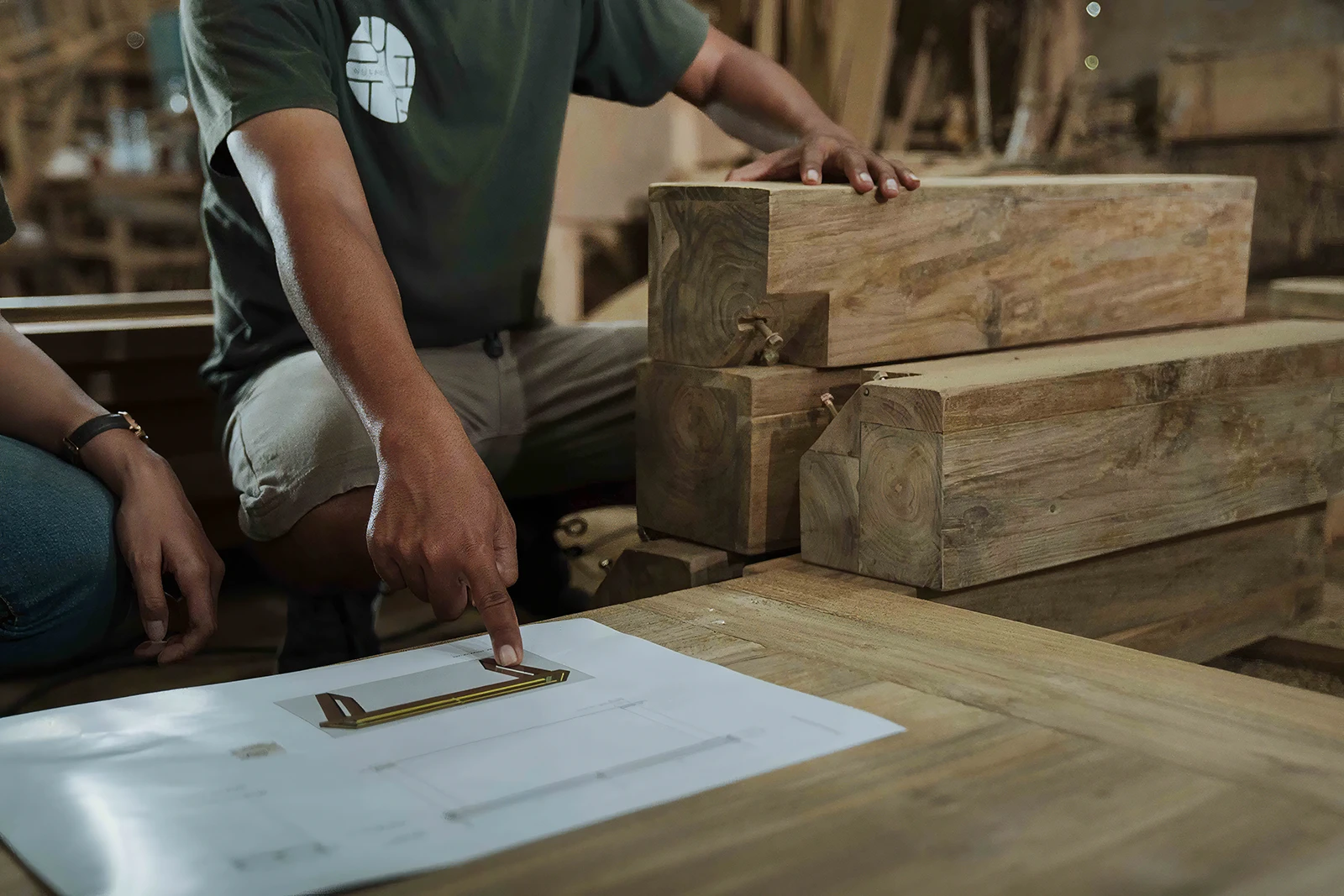 Furniture designer reviewing reclaimed teak samples and furniture drawings during the design development stage.