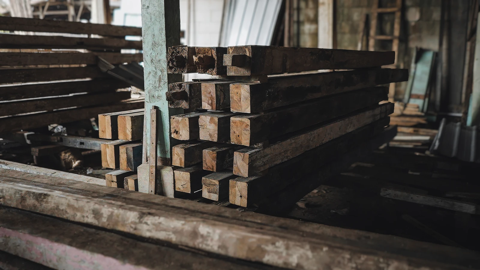 Stacks of reclaimed teak beams stored at Nusantara Lifestyle's timber facility, showing recovered wood ready for processing and reuse.